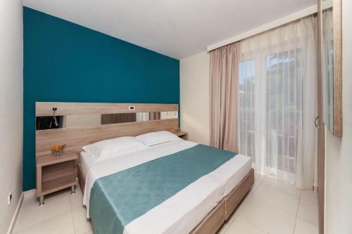 una camera con un grande letto e una parete blu di Apartments Katoro Plava Laguna a Umag (Umago)