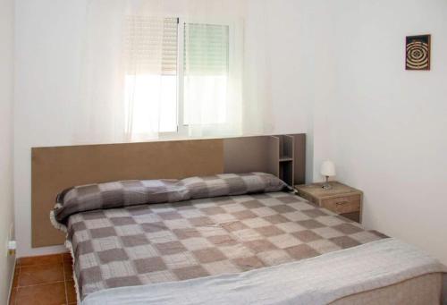 um quarto com uma cama com um cobertor xadrez em Bonito apartamento en Garrucha em Garrucha
