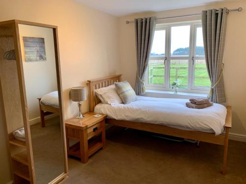Schlafzimmer mit einem Bett, einem Spiegel und einem Fenster in der Unterkunft Grange Farm Cottages in Wressell
