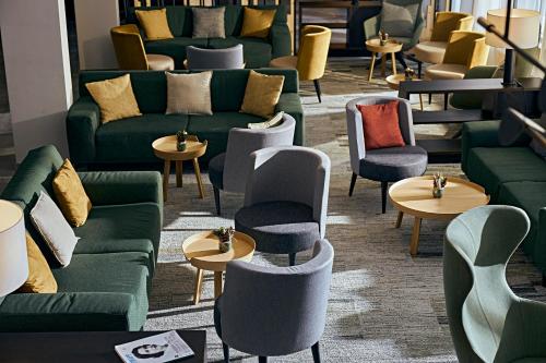 a waiting room with couches and tables and chairs at ROBINSON Landskron in Landskron