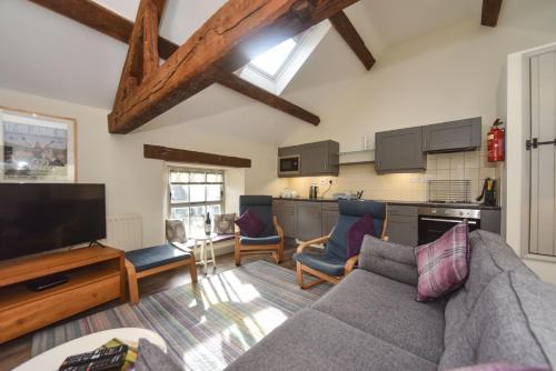 a living room with a couch and a kitchen at Church Farm Holiday Cottages - Winnets Cottage in Ashbourne
