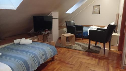 a bedroom with a bed and two chairs and a television at Car Royal Apartments and Rooms in Novi Sad