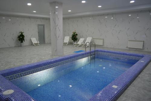 a large swimming pool in a room with chairs at Гостиничный комплекс "Коктобе" in Aktobe