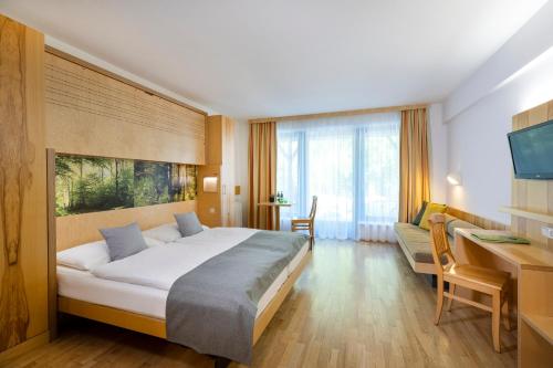 una camera d'albergo con un grande letto e una scrivania di JUFA Hotel Bruck an der Mur - im Weitental a Bruck an der Mur