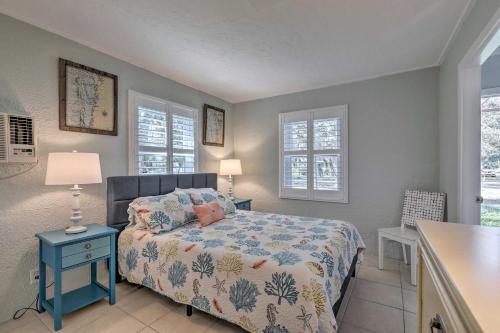 a bedroom with a bed and a table and two windows at Cozy Crystal Beach Cottage Walk to Shoreline in Crystal Beach