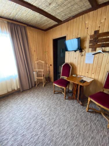 a room with a table and two chairs and a television at Guest house Shulc in Mizhhirʼʼya