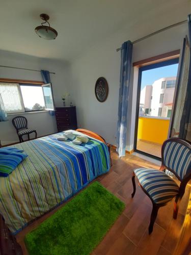 a bedroom with a bed and a chair and a window at MARIA INÊS HOUSE in Nazaré