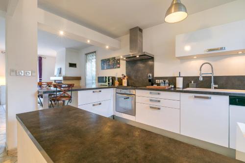 une cuisine avec des armoires blanches et un comptoir dans l'établissement Charmante Maison Climatisée avec son Jardin à 5 minutes de DIJON, à Saint-Apollinaire