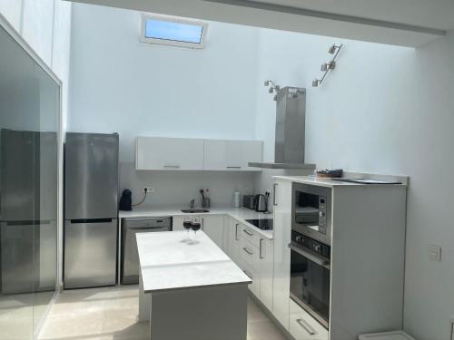 une cuisine avec des comptoirs blancs et des appareils en acier inoxydable dans l'établissement Villa Ashdene - luxury modern villa with large heated pool wifi uk tv bar & BBQ, à Playa Blanca