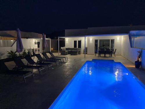 - une piscine avec des chaises et une terrasse la nuit dans l'établissement Villa Ashdene - luxury modern villa with large heated pool wifi uk tv bar & BBQ, à Playa Blanca