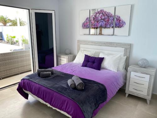 a bedroom with a bed with purple sheets and pillows at Villa Ashdene - luxury modern villa with large heated pool wifi uk tv bar & BBQ in Playa Blanca