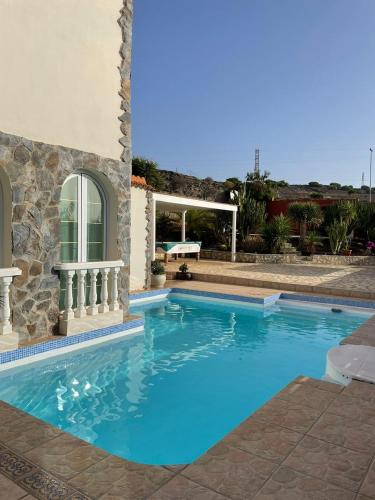 a large blue swimming pool next to a building at Casa Macken con piscina climatizada y jacuzzi in San Bartolomé