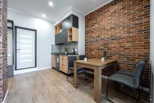a kitchen with a brick wall and a table and chairs at Стильная квартира с балконом на 5 Фонтана in Odesa