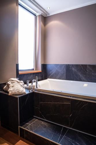 a bathroom with a bath tub and a window at Hotel Master in Brescia