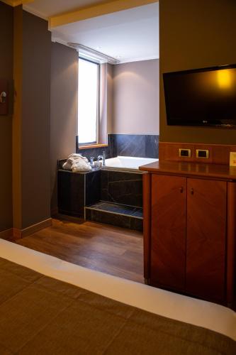 a bathroom with a bath tub and a television at Hotel Master in Brescia