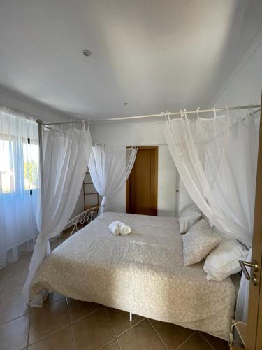een slaapkamer met een hemelbed en witte gordijnen bij Vila Sal-Moura in Moura
