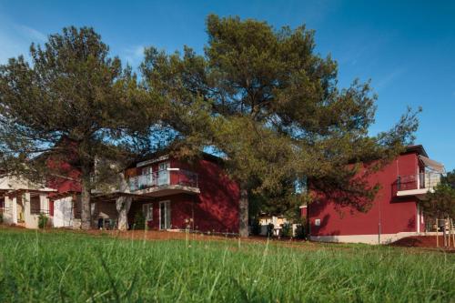 a red building with trees in front of it at Apartments Katoro Plava Laguna in Umag
