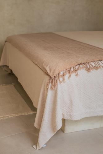 a bed with a beige bedspread on it at La Bohème Sayulita in Sayulita