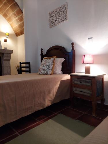 a bedroom with a bed and a table with a lamp at Moira - Alojamento Local in Reguengos de Monsaraz