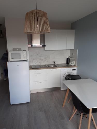 eine Küche mit einem weißen Kühlschrank und einem Tisch in der Unterkunft Les Sables d'Olonne in Les Sables-dʼOlonne