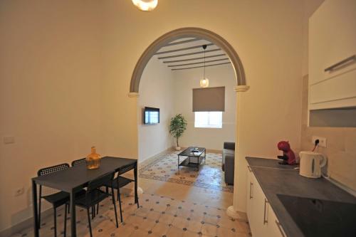 cocina y comedor con arco y mesa en Apartamentos Casa Rosaleda, en Jerez de la Frontera