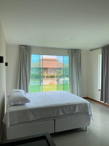 a bedroom with a bed and a large window at Nosso Recanto in Porto de Sauipe