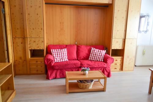 a living room with a red couch and a table at Bilocale Cervinia Cielo alto sulle piste in Breuil-Cervinia