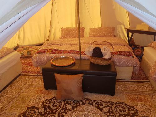 a bedroom with a bed and a table in a tent at Starwatching Private Camp in Ḩawīyah