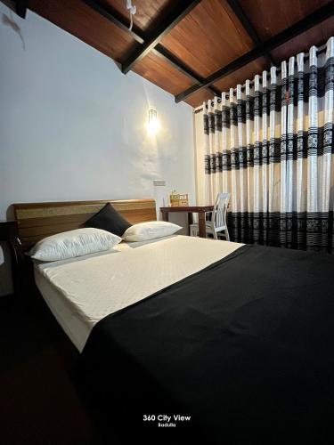 a bedroom with a bed and a table and a window at 360 City View in Badulla
