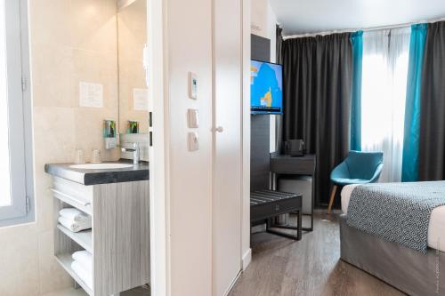 a hotel room with a sink and a bed at Hôtel Versailles Chantiers in Versailles