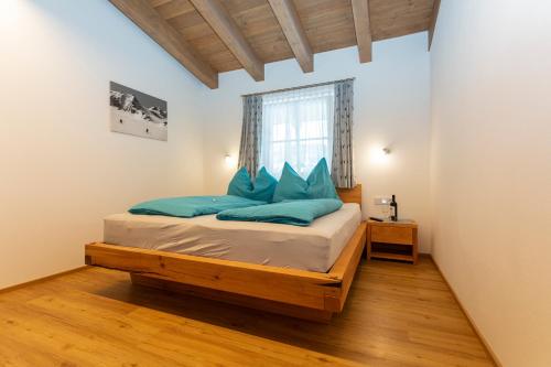 a bedroom with a bed with blue pillows and a window at Ferienwohnungen Egg in Fieberbrunn