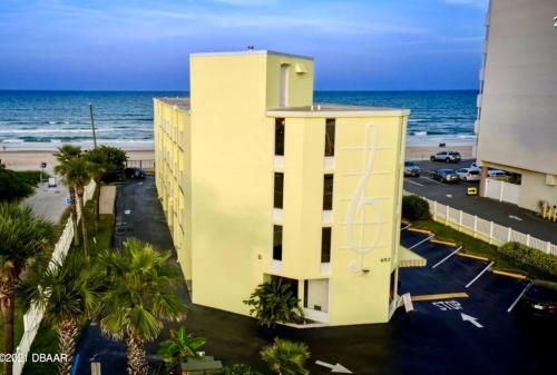 a yellow building with the ocean in the background at Coastal Sands - Ocean View at Symphony Beach Club! in Ormond Beach