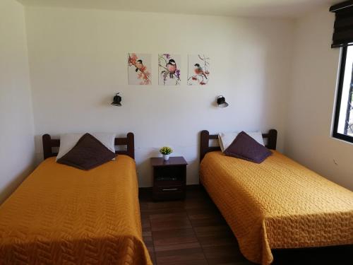 two beds in a room with yellow sheets at Chapelet Hostal in Tababela