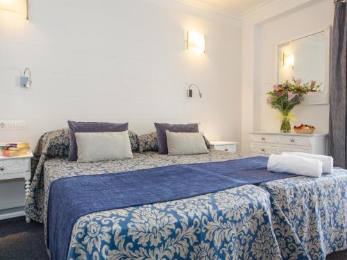 een slaapkamer met een bed met een blauwe en witte deken bij Hotel Villa Singala in Port de Pollença