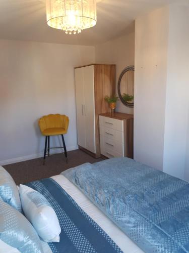 1 dormitorio con 1 cama azul y 1 silla en Home from Home 3 bedroom pier front stay, en Donaghadee