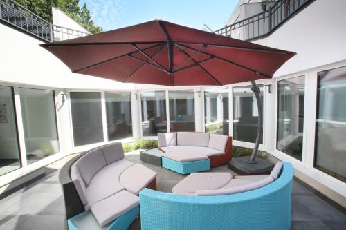 a patio with two chairs and an umbrella at 25h SPA-Residenz POOLs IN & OUT, private Garden & Beach in Neusiedl am See