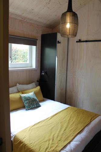 a bedroom with a bed with a yellow blanket and a window at Halte Liempde Logies in Liempde