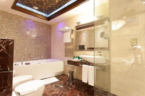 een badkamer met een bad, een toilet en een wastafel bij Metropolis Hotel in Bistriţa