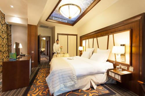 a hotel room with a large bed and a man standing in the doorway at Metropolis Hotel in Bistriţa