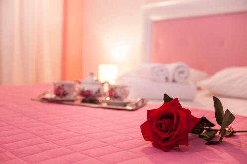 a red rose sitting on a pink bed with a rosephasis at Filoxenia Sea View in Parga