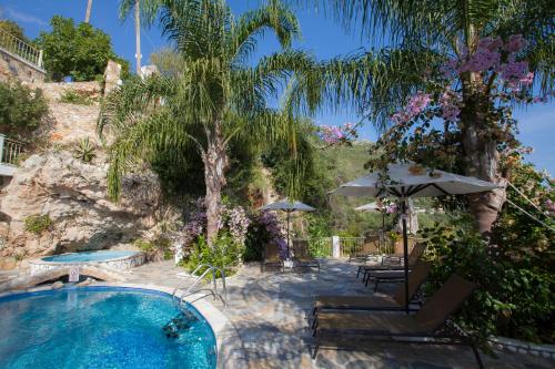 a pool with a palm tree and chairs and an umbrella at Filoxenia Sea View in Parga