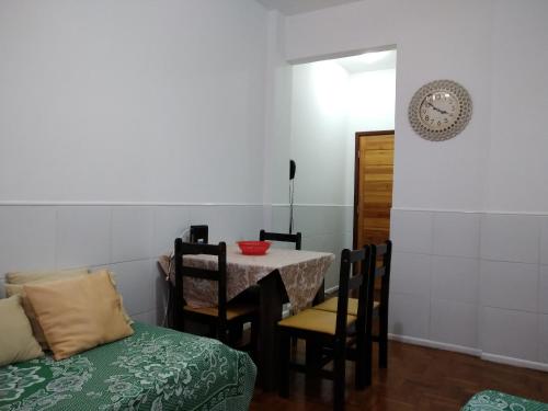 comedor con mesa, sillas y reloj en Apartamento Farol da Barra Salvador, en Salvador