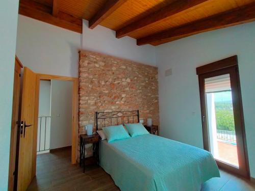 1 dormitorio con cama y pared de ladrillo en Más del Sandungo, en Els Ibarsos