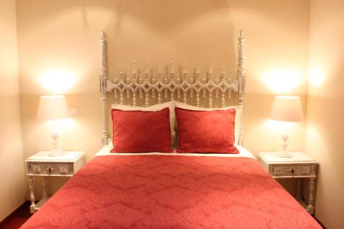 ein Schlafzimmer mit einem Bett mit roten Kissen und zwei Lampen in der Unterkunft Panoramic City View Apartment - Guimarães in Guimarães