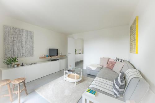 un soggiorno bianco con divano e TV di Trendy Apartments as Base to Discover Ghent a Gand