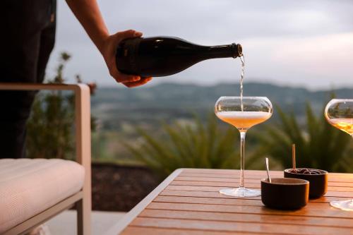 a person pouring wine into a wine glass on a table at Tavarneta Estate in Dobrovo
