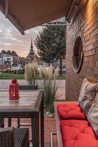 a patio with a wooden table and a red couch at Hotel Stadthafen Stade in Stade