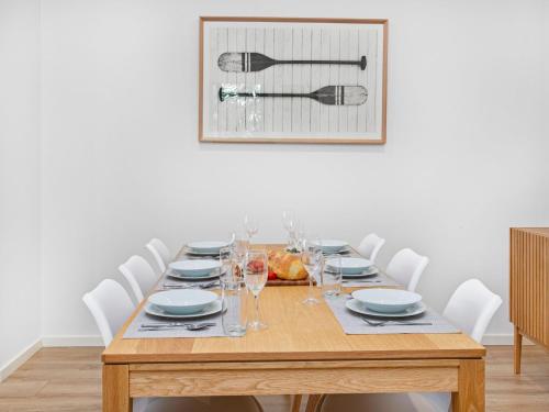 a dining room table with white chairs and a picture at Bikinis and Martinis in Kiama