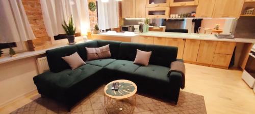 イェレニャ・グラにあるApartament Podwaleのリビングルーム(緑のソファ付)、キッチンが備わります。