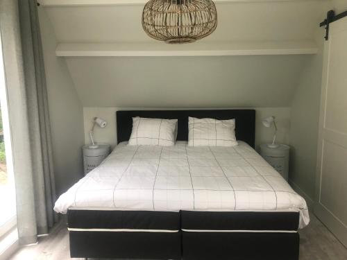 Schlafzimmer mit einem Bett mit weißer Bettwäsche und einem Kronleuchter in der Unterkunft Vakantiehuis Zilt in Ouddorp